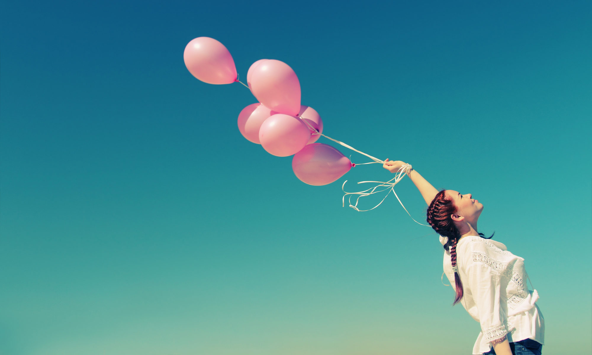 Young redhead woman holding pink balloons
